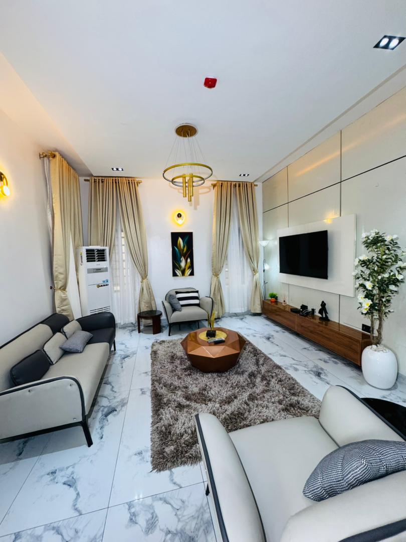 A living room with cream sofas and a wall-mounted television
