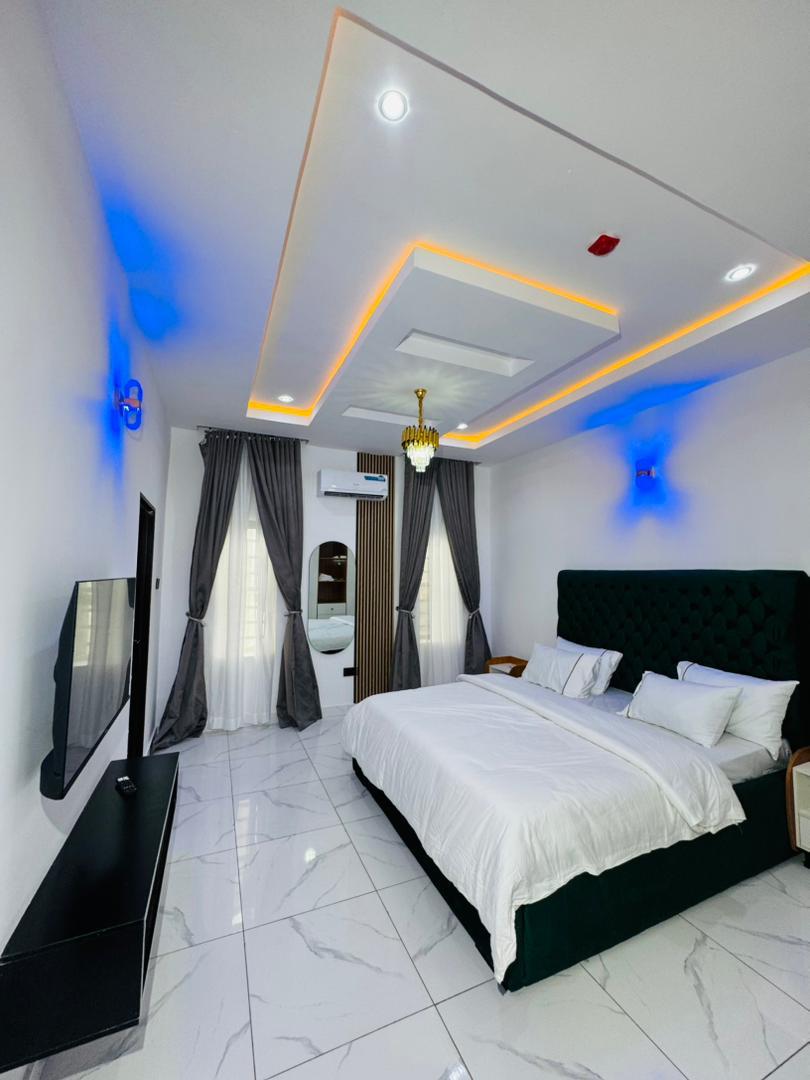 A bedroom with a dark green headboard and white bedding