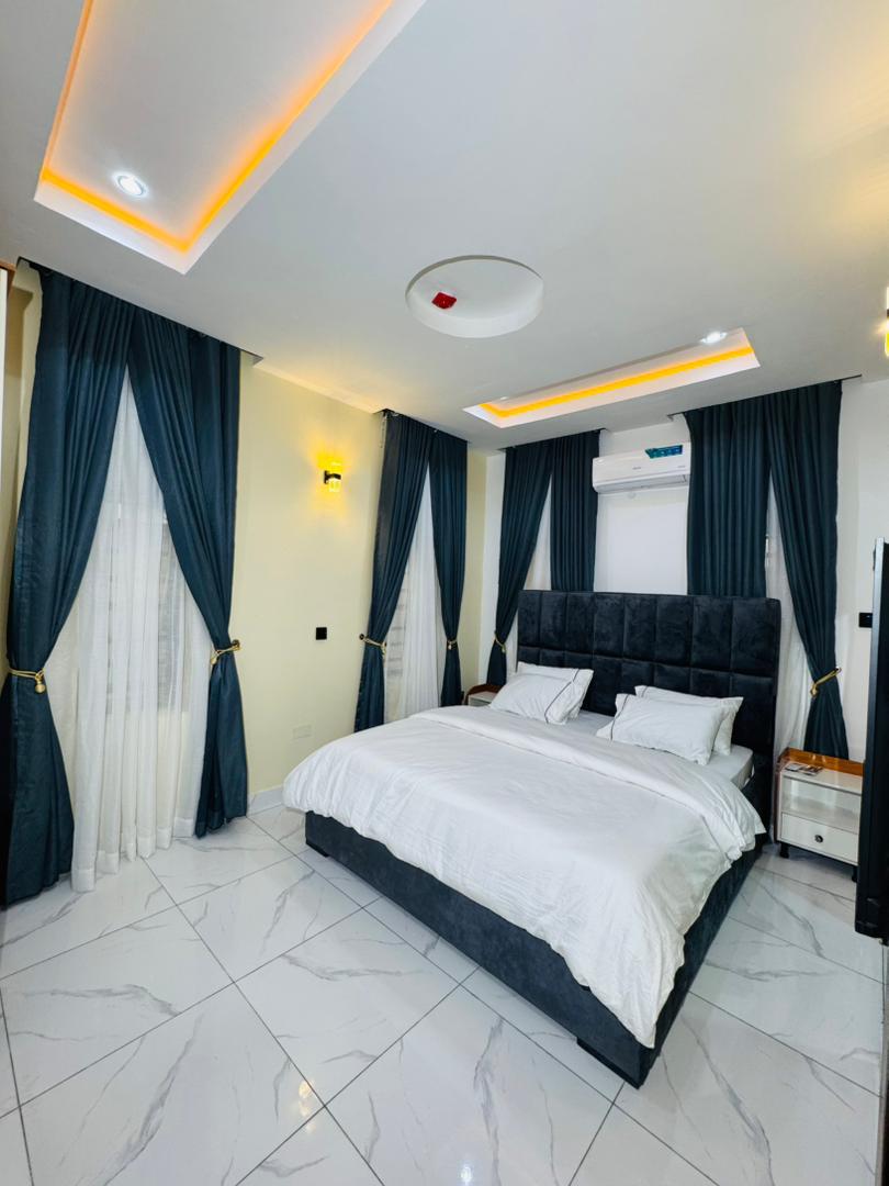 A bedroom with teal curtains and a dark padded headboard