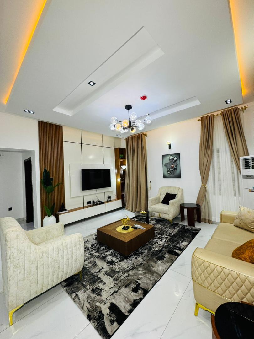 A living room with a chandelier and cream armchairs