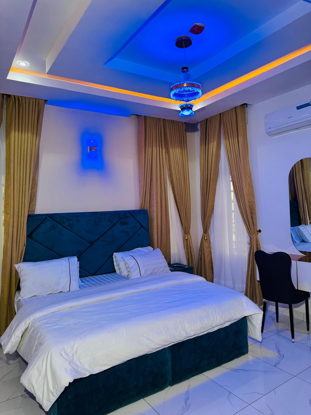 A bedroom with a navy diamond-stitched headboard
